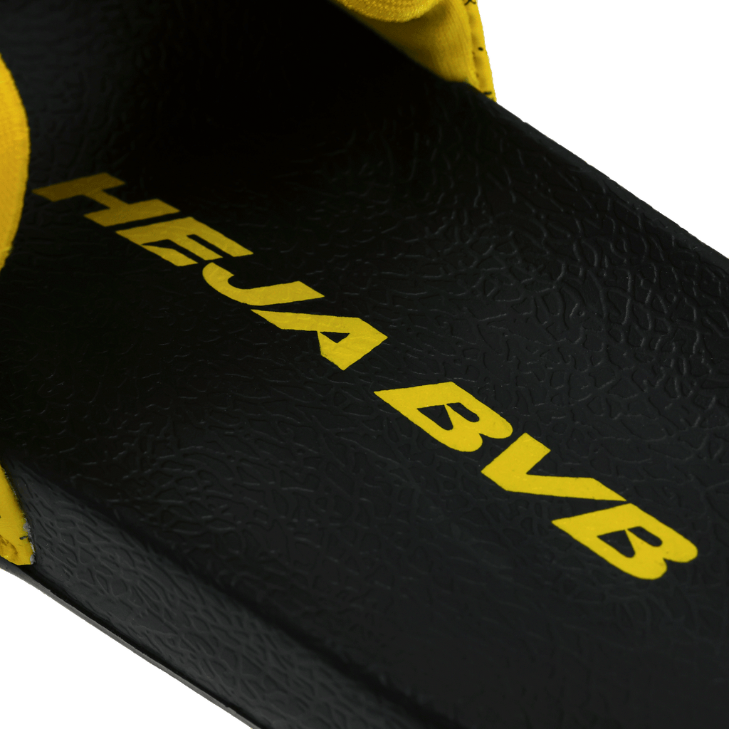 Black-and-yellow BVB bath slippers for kids, with a black insole featuring yellow "Heja BVB" lettering—perfect as fan merchandise or a summer accessory.