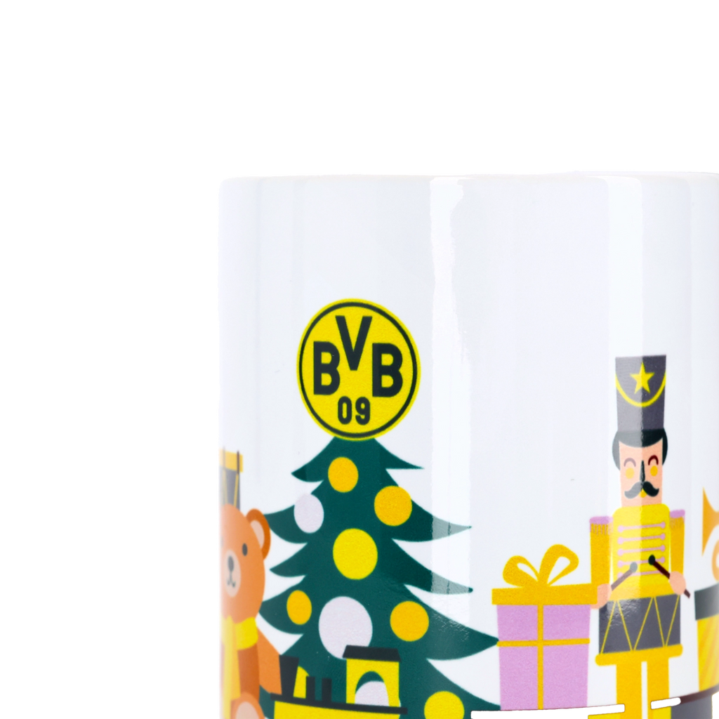 クリスマスツリー、くるみ割り人形、クマ、そして黒と黄色のBVBロゴなど、お祝いのモチーフが描かれた白いBVBのクリスマスマグカップ。