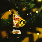 Goldfarbener BVB-Weihnachtsanhänger in Form von Ernie mit gelbem BVB 09 Logo aus Glas, weihnachtlich dekoriert, an einem grünen Weihnachtsbaum aufgehängt.