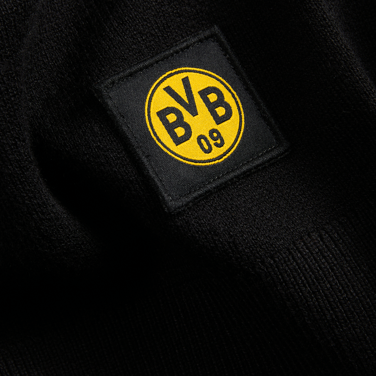 Nahaufnahme eines schwarzen Stoffes mit dem schwarzgelben BVB-Logo des Borussia Dortmund 09.