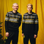 Schwarzgelber BVB-Winterpullover im Norweger-Design mit Schneeflocken-Muster, getragen von zwei Männern vor einem gelben Hintergrund. Perfekt als Fanartikel für kalte Tage.