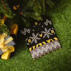 Winterpullover im Norweger-Design von Borussia Dortmund mit BVB-Logo und Schneeflocken, in schwarzgelben Farben unter einem Weihnachtsbaum arrangiert.