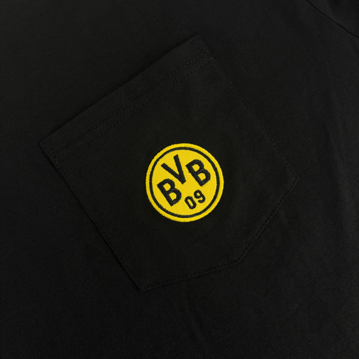 Black chest pocket with a yellow BVB logo, close-up. Borussia Dortmund fan merchandise.
