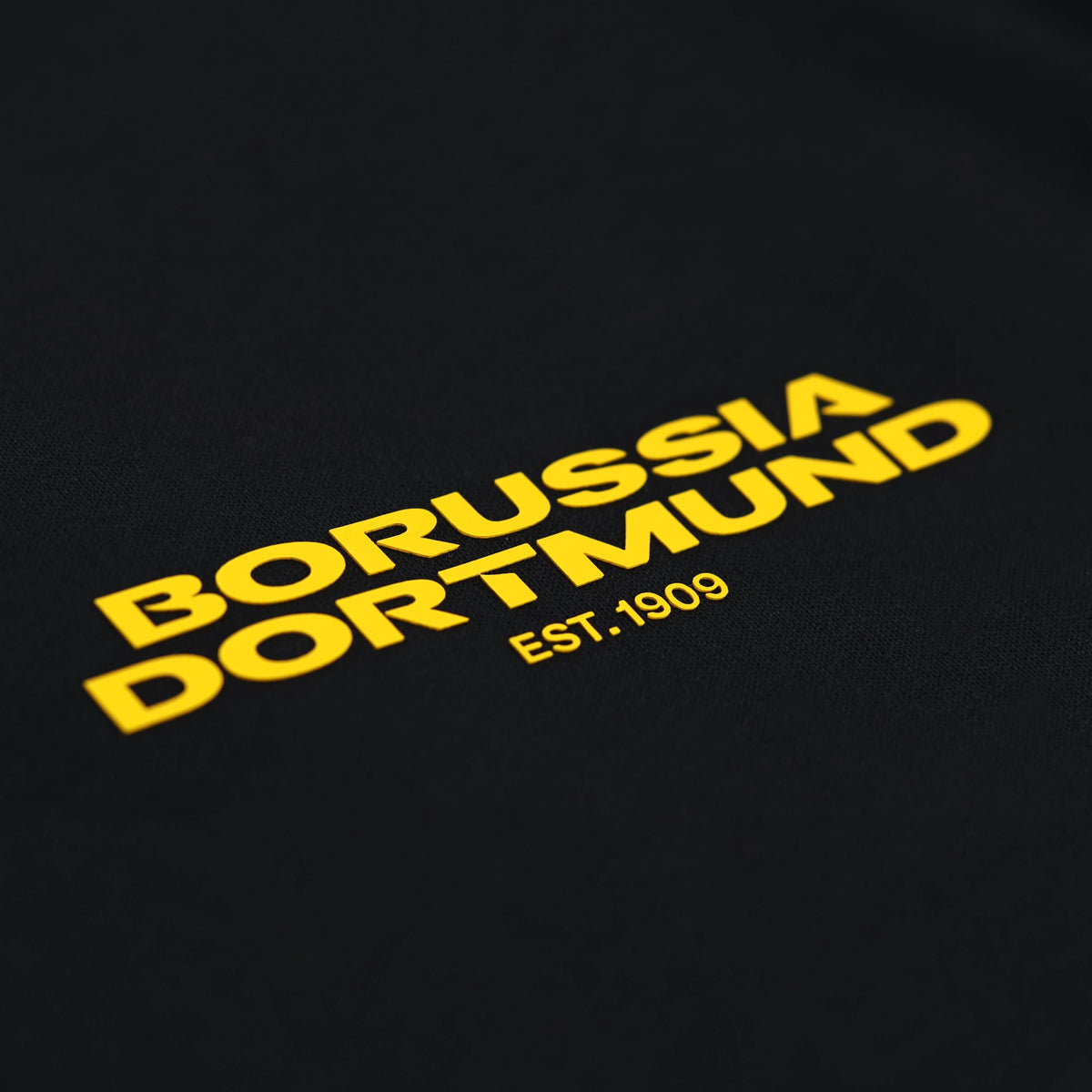 Schwarzes BVB-T-Shirt mit gelbem Borussia Dortmund Schriftzug und dem Gründungsjahr EST.1909 auf der Vorderseite.