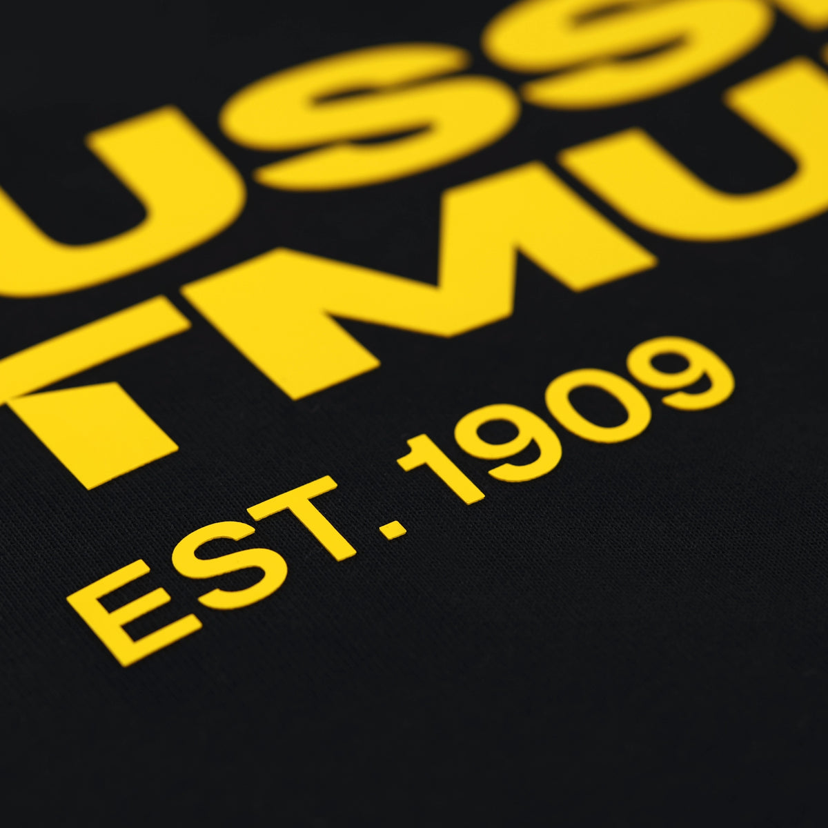 Schwarzes T-Shirt mit gelbem Schriftzug 'EST. 1909' und Borussia Dortmund Schriftzug, Detailaufnahme.