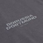 Nahaufnahme eines grauen BVB-Shirts mit weißem Borussia Dortmund Schriftzug und EST.1909 Aufdruck.