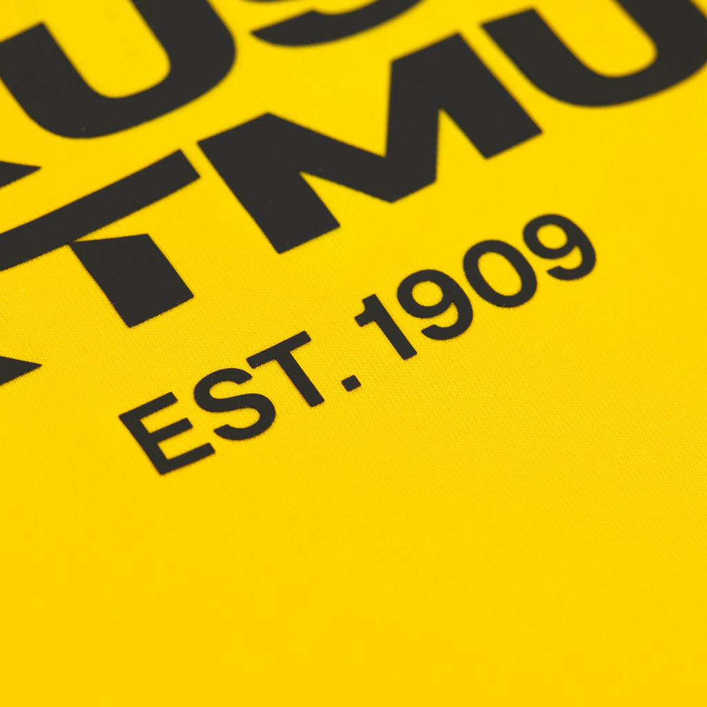 Detailaufnahme des BVB Urban T-Shirts in Gelb mit schwarzer Aufschrift 'EST. 1909' und typischen schwarzgelben Vereinsfarben.