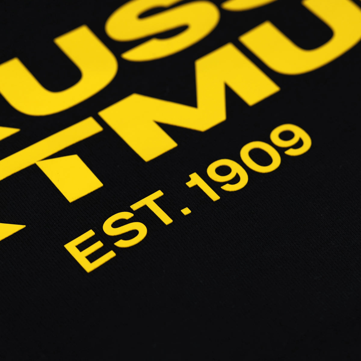 Detailaufnahme eines schwarzen BVB-Hoodies mit gelbem Schriftzug 'EST. 1909', angelehnt an das Design von Borussia Dortmund.