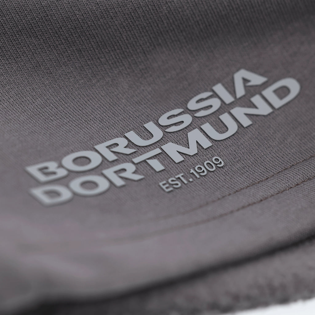 Graue BVB Urban Sweatshorts mit aufgedrucktem Borussia Dortmund Logo und EST. 1909 Schriftzug in Nahaufnahme.