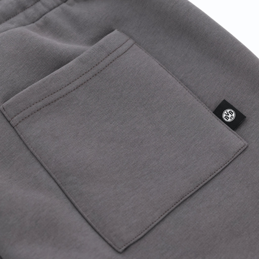 Graue BVB Urban Sweatshorts in der Detailansicht mit Tasche und schwarzweißem BVB-Logo, ideal als Fanartikel oder Streetwear geeignet.