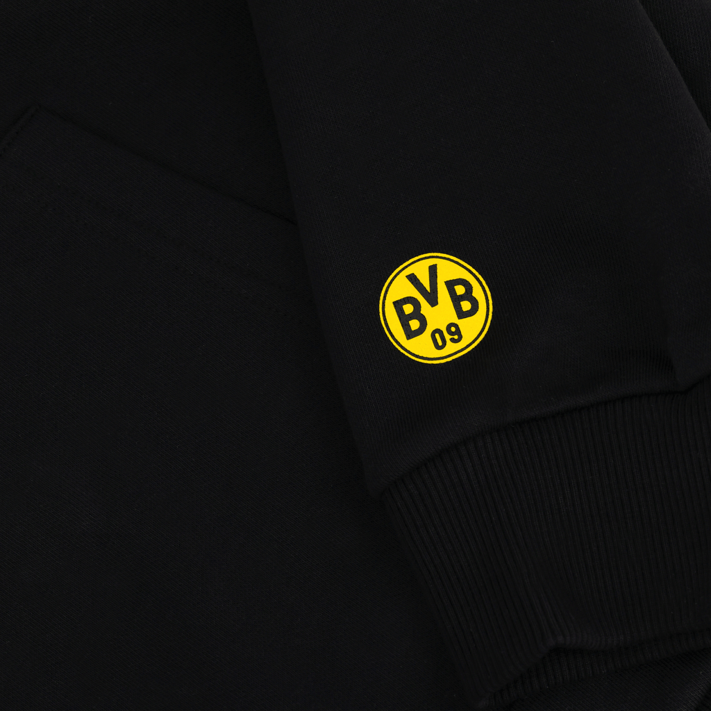 Vista dettagliata di una felpa con cappuccio nera del BVB con il logo giallo “BVB 09” sulla manica. Articolo ufficiale per i tifosi del Borussia Dortmund.