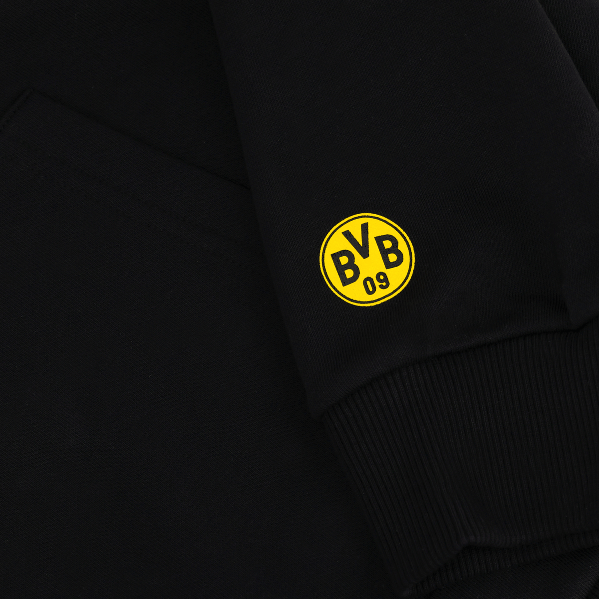 Vista dettagliata di una felpa con cappuccio nera del BVB con il logo giallo “BVB 09” sulla manica. Articolo ufficiale per i tifosi del Borussia Dortmund.