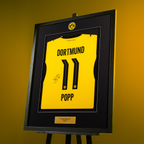 BVB-Trikotrahmen mit signiertem gelbem Alex Popp Trikot, Rückansicht mit der Nummer 11, stilvoll eingerahmt in schwarzgelbem Design.