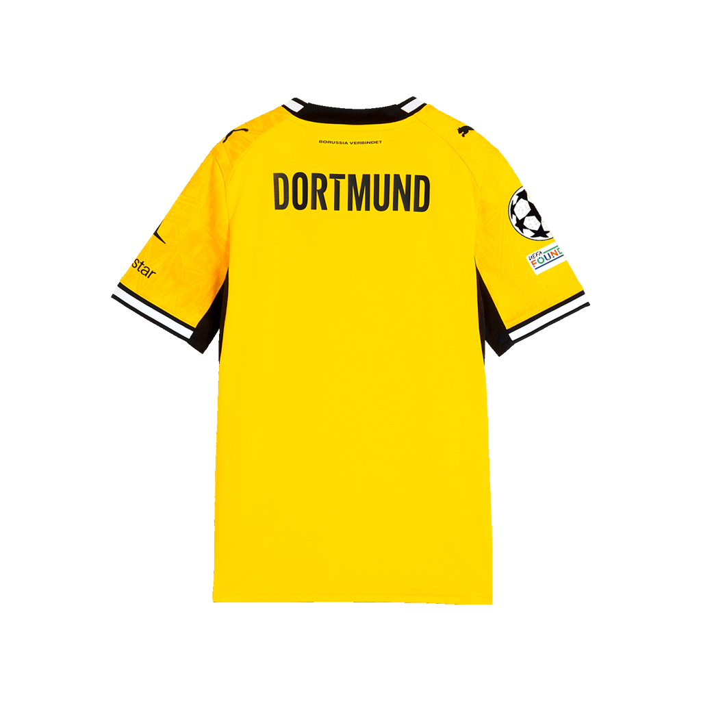 La imagen muestra la vista trasera de la camiseta amarilla de local del BVB para la temporada 26-27 para niños, con la inscripción «DORTMUND», el logotipo de PUMA y el logotipo de la Liga de Campeones en la manga.