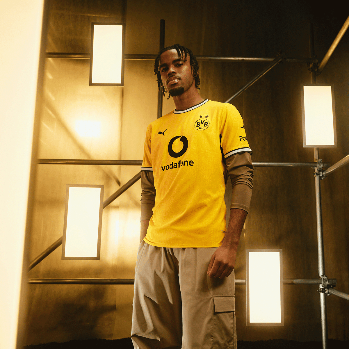 Das schwarzgelbe BVB Heimtrikot der Saison 26/27 mit BVB-Emblem, Puma-Logo und Vodafone-Aufdruck, präsentiert von einem Model vor moderner Kulisse.