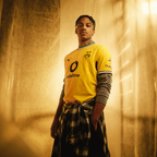 Das gelbe BVB-Heimtrikot der Saison 26/27 mit schwarzem Kragen, BVB-Emblem, Vodafone- und Polestar-Logos, präsentiert von einer stehenden Person.