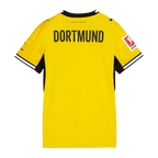Vista trasera de la camiseta de local del BVB de la temporada 26/27 para mujer, en colores negro y amarillo, con la inscripción «DORTMUND» y los logotipos de la Bundesliga y de Puma visibles en las mangas.