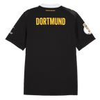 Camiseta negra de visitante del BVB de la temporada 2026/27, vista desde atrás, con la inscripción «DORTMUND» en amarillo y el escudo del club en las mangas.
