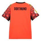 Red BVB goalkeeper jersey from the 26-27 season with "DORTMUND" lettering on the back, a black trim around the collar, and a geometric sleeve pattern in red and black.