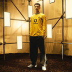 Le maillot domicile à manches longues du BVB pour la saison 2026/27, aux couleurs noir et jaune, orné du logo PUMA, du logo Vodafone et de l'emblème du BVB, présenté par un mannequin devant un décor moderne.