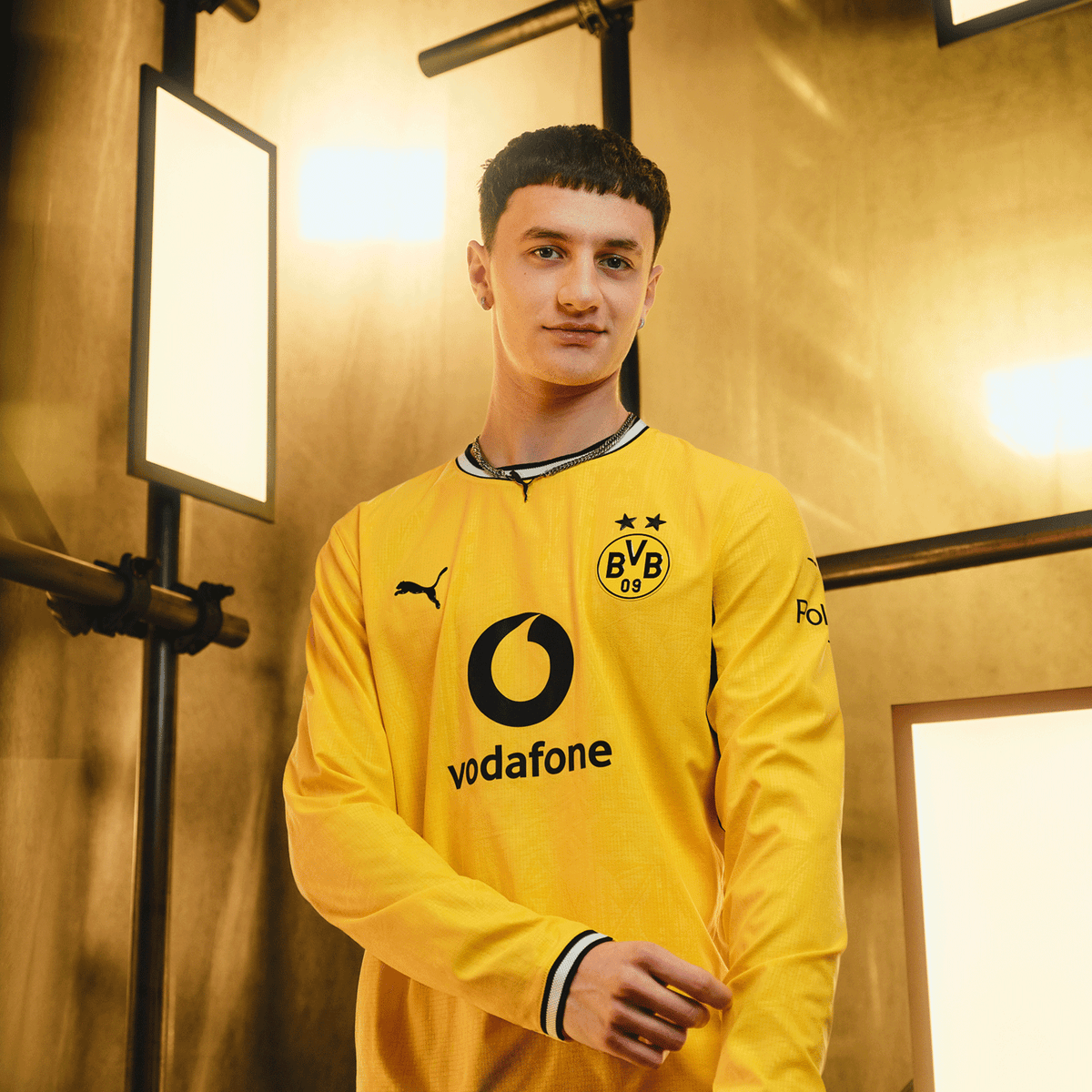 Langärmliges BVB Heimtrikot der Saison 2026-2027 in schwarzgelb mit Puma-Logo, BVB-Emblem und Vodafone-Logo, präsentiert von einem Modell in moderner Kulisse.