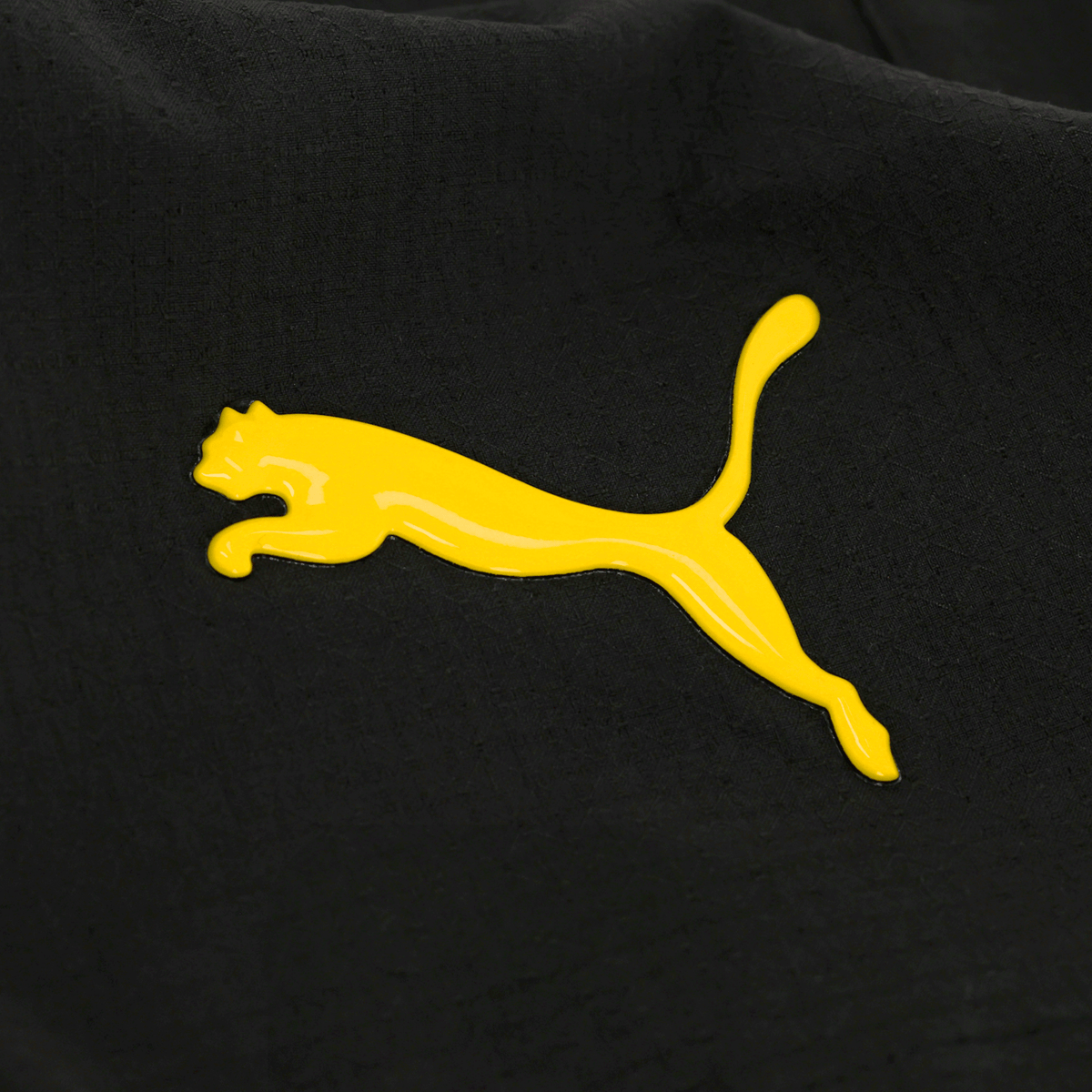 Gros plan sur le logo PUMA jaune sur le tissu noir du short de football BVB 26/27 Authentic.