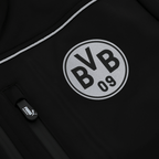 这款由BVB 09和PUMA联名推出的黑色软壳工装夹克，配有白色BVB标志和拉链细节，既适合球迷穿着，也适合工作场合。
