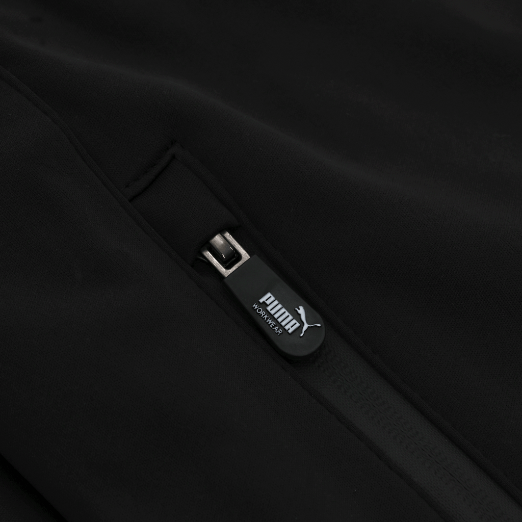 Close-up of a side zipper on the black BVB Puma Workwear softshell jacket, ideal for fans and work in a black-and-yellow design.
