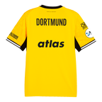 La camiseta local del BVB de la temporada 26-27, en negro y amarillo, vista desde atrás, lleva la inscripción «DORTMUND», mangas negras y los logotipos de los patrocinadores. Pertenece a la línea de ropa deportiva de PUMA y es un artículo muy popular entre los aficionados.