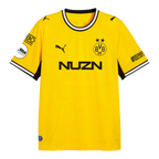 La camiseta de local del BVB para la temporada 26-27, de color negro y amarillo, de PUMA, muestra el escudo del BVB, el logotipo de PUMA, la inscripción «NUZN» y los logotipos de los patrocinadores en ambas mangas, vista de frente.