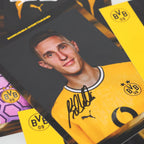 Set di figurine autografate del BVB della stagione 2026/27 con firme stampate; il giocatore in primo piano indossa la maglia gialla con lo stemma del BVB e il logo PUMA.