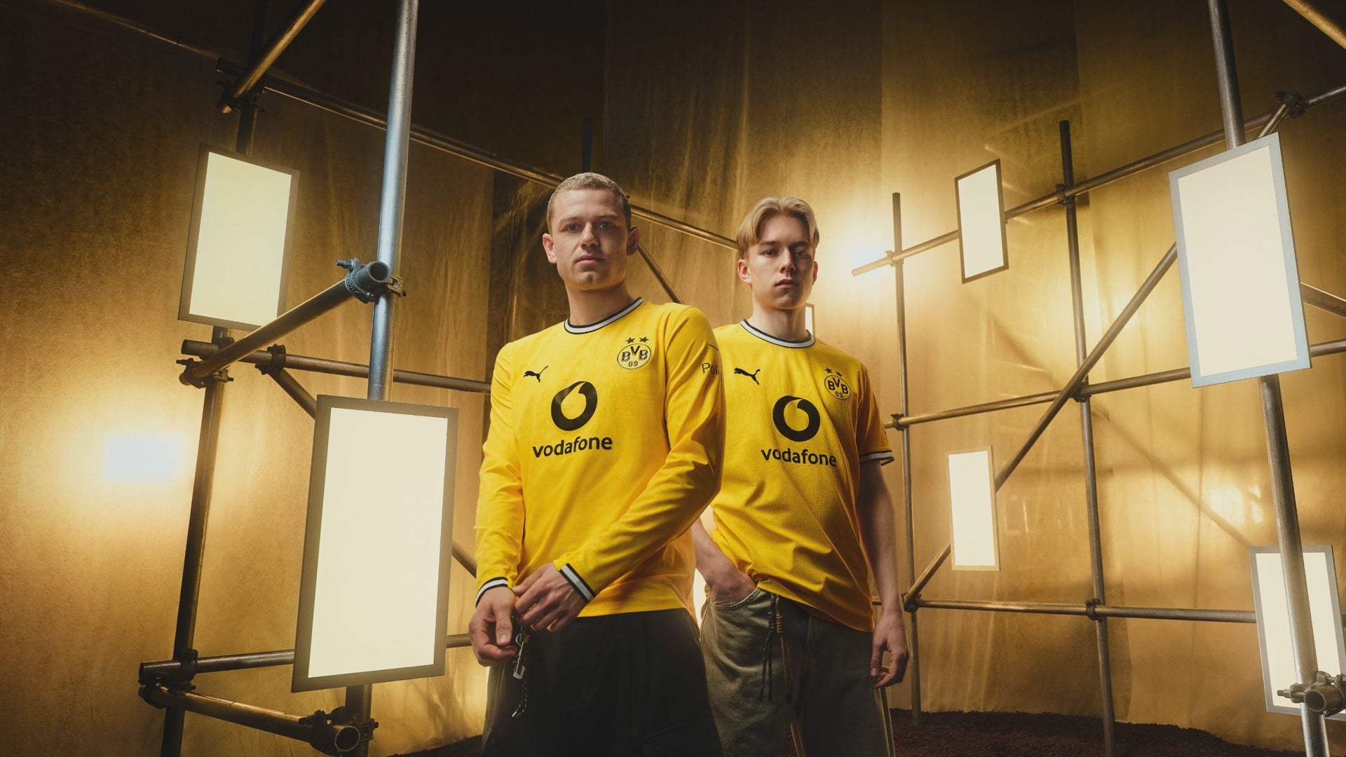 Das Video zeigt ein Foto von den beiden BVB Spielern Julian Ryerson und Daniel Svensson, wie sie nebeneinander stehen und das Authentic Heimtrikot der Saison 26/27 tragen. Es wird an folgende Details des Trikots herangezoomt: die PUMA Katze auf der linken Brust, das BVB Logo auf der rechten Brust und den Stoff des Trikots. Diese Details werden in den nächsten Abschnitten thematisiert.
